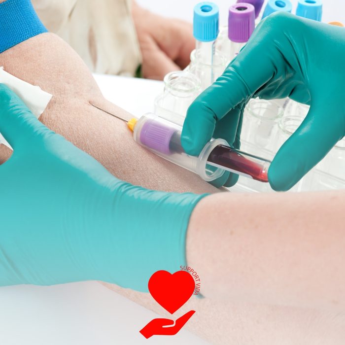 Profissional de luvas coletando sangue do braço do paciente para exames laboratoriais