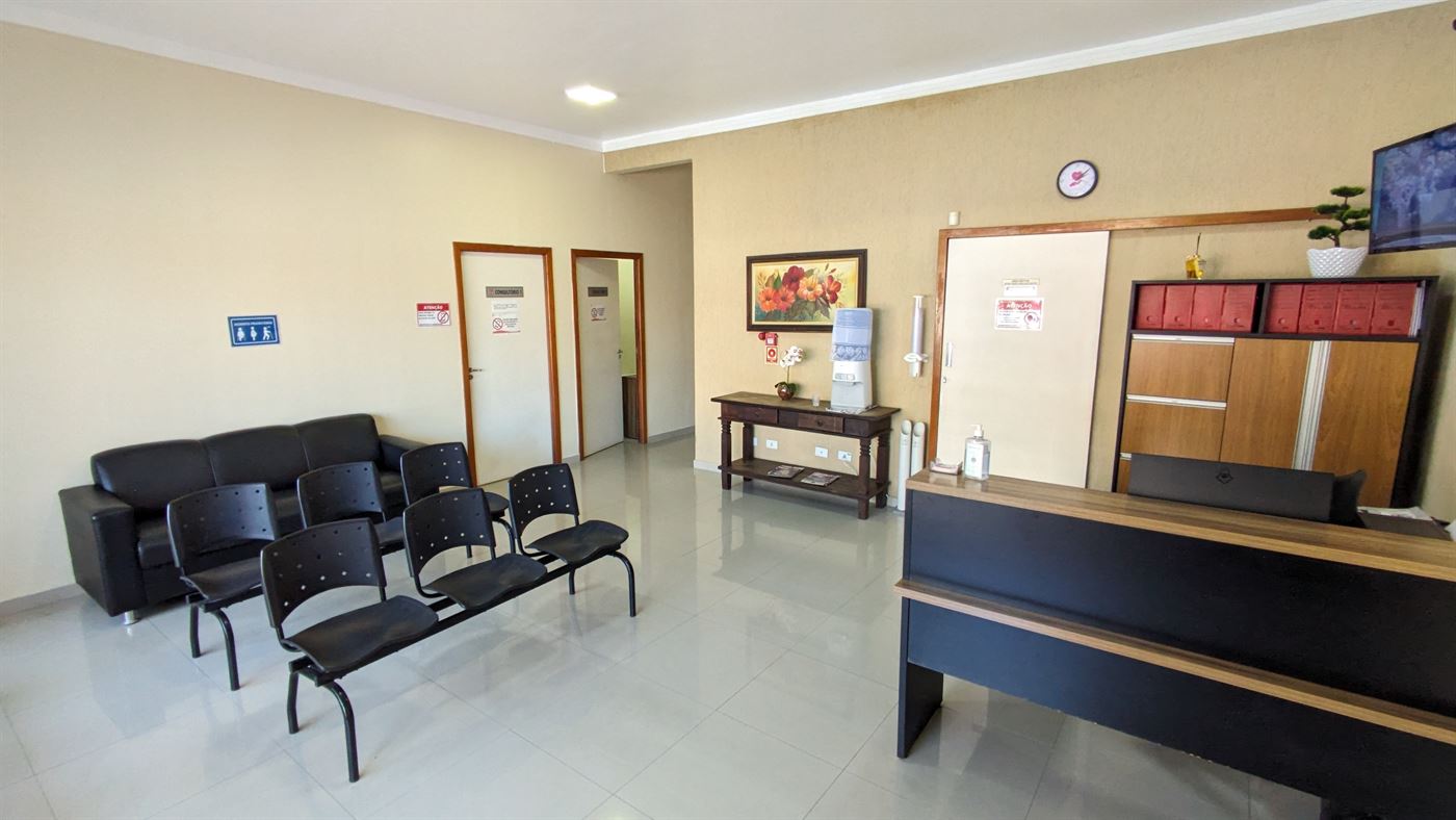 Sala de espera com sofá e cadeiras ao lado do balcão de recepção da clínica