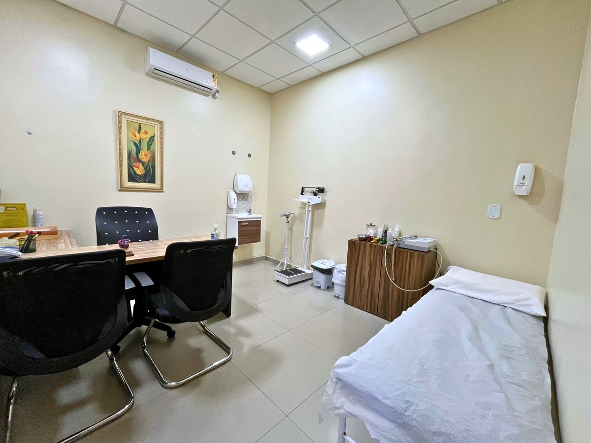 Sala de exames com maca, balança e mesa de atendimento